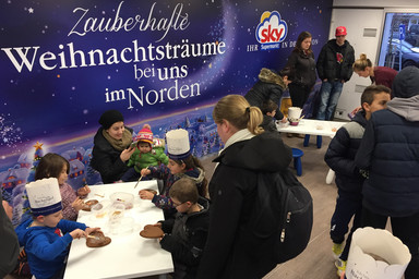 People sitting at a table and wall with "Zauberhafte Weihnachtsträume bei uns im Norden"-Lettering Image 3
